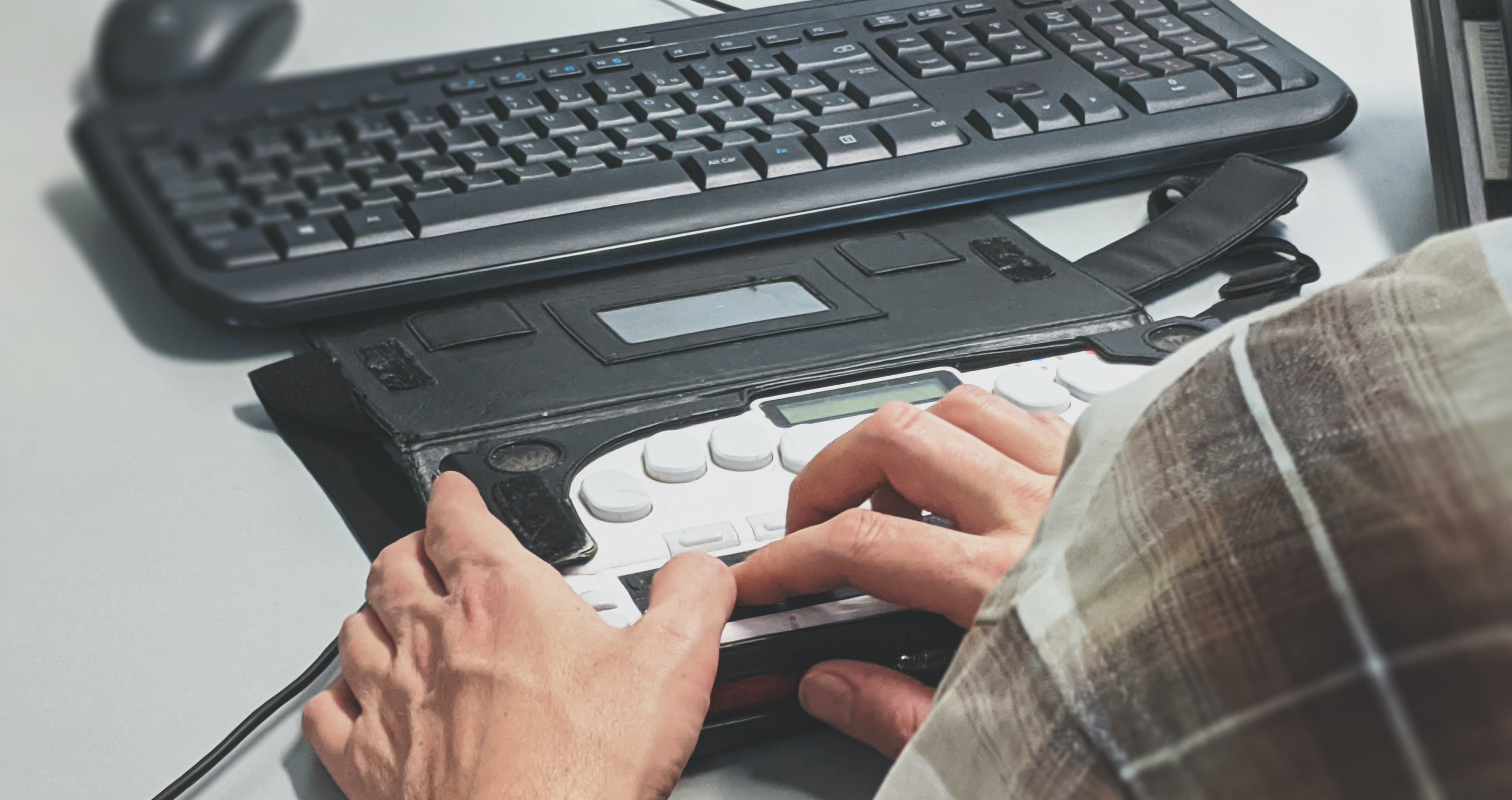 Person using a refreshable braille display attached to a computer