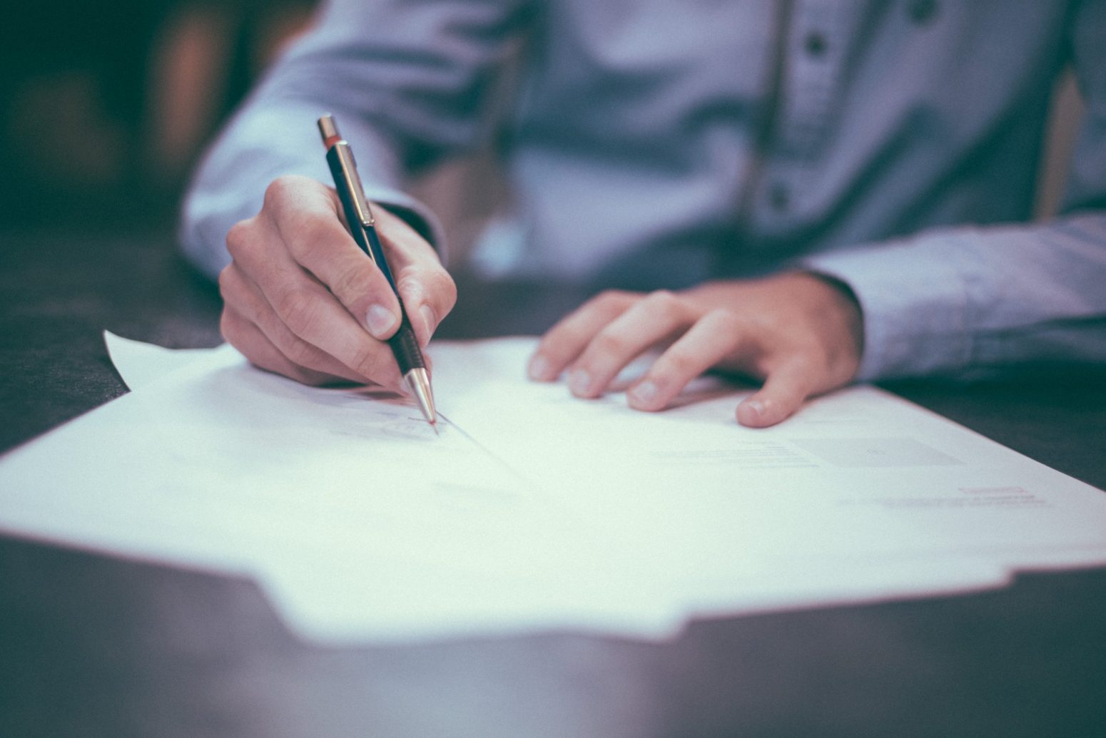 A man writing on a piece of paper with a pen