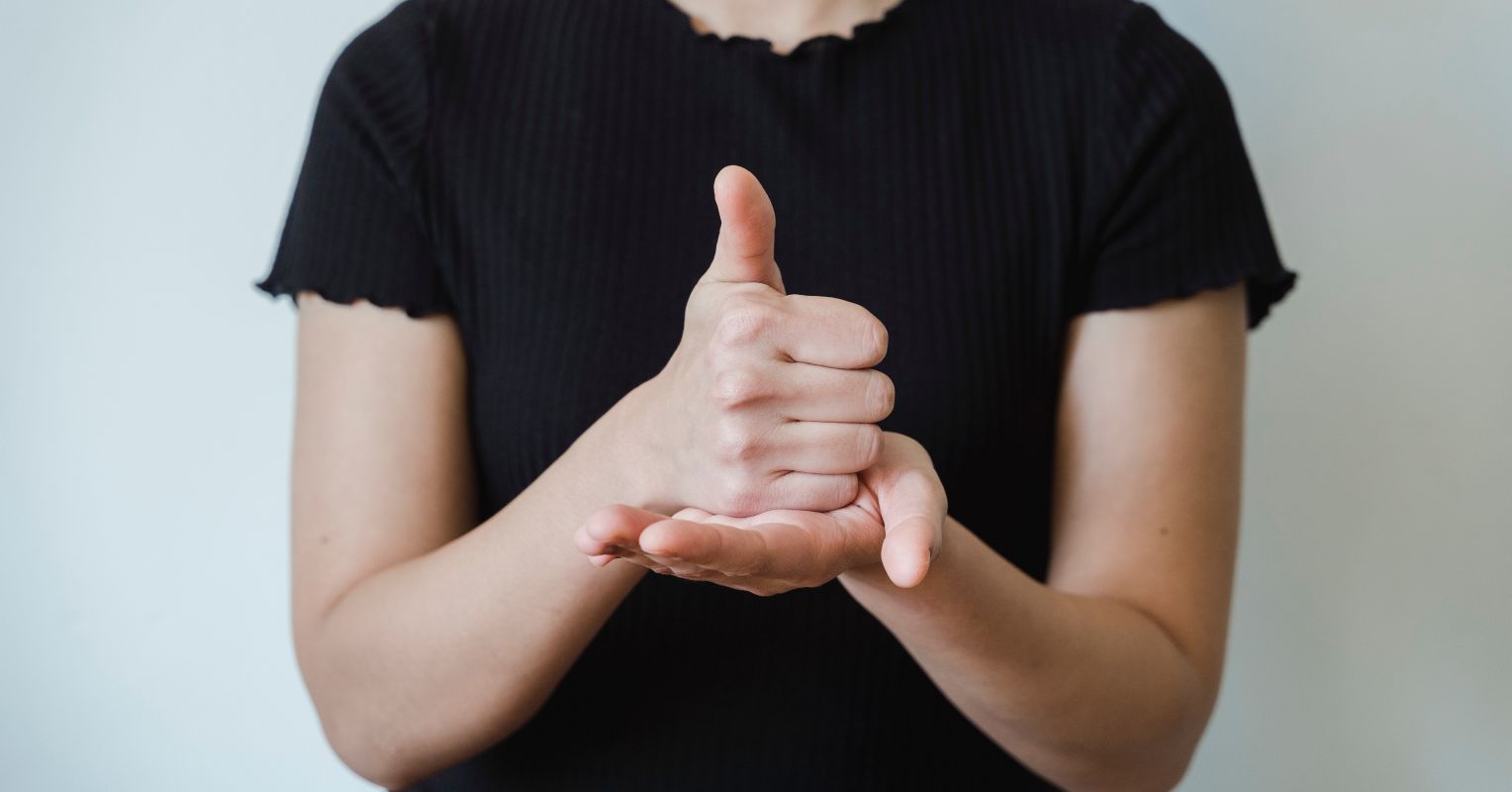 Thumbs up over a flat palm, forming the language sign for help