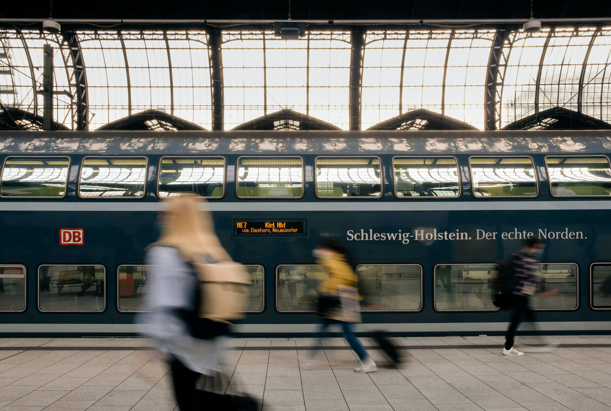 Passengers walking past a train stopped at a station in Germany